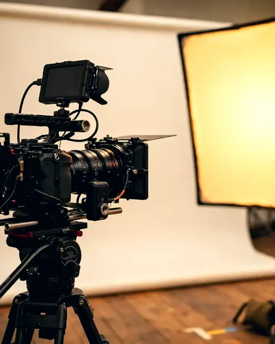 A cinema camera on a tripod beside a soft light